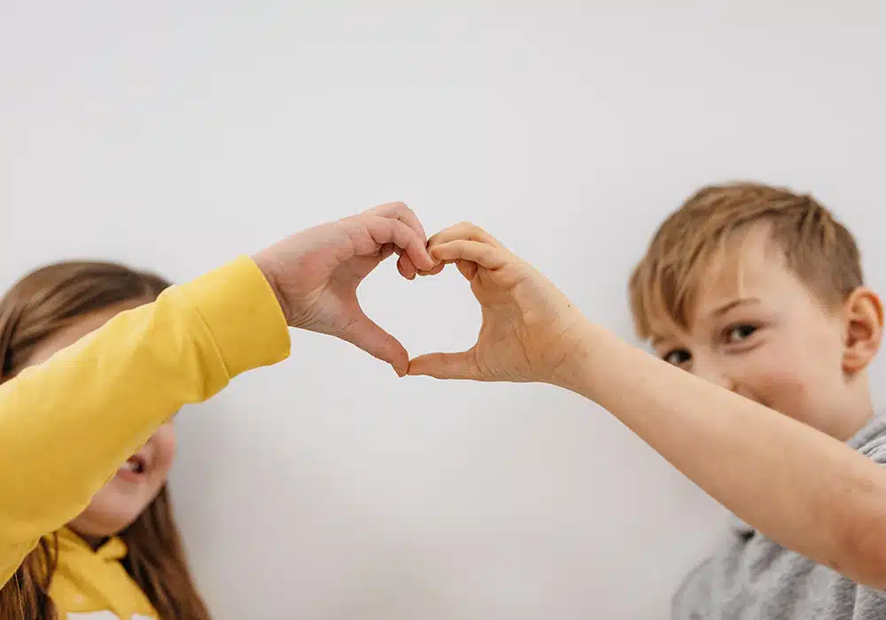 Junge und Mädchen formen mit den Händen ein Herz.